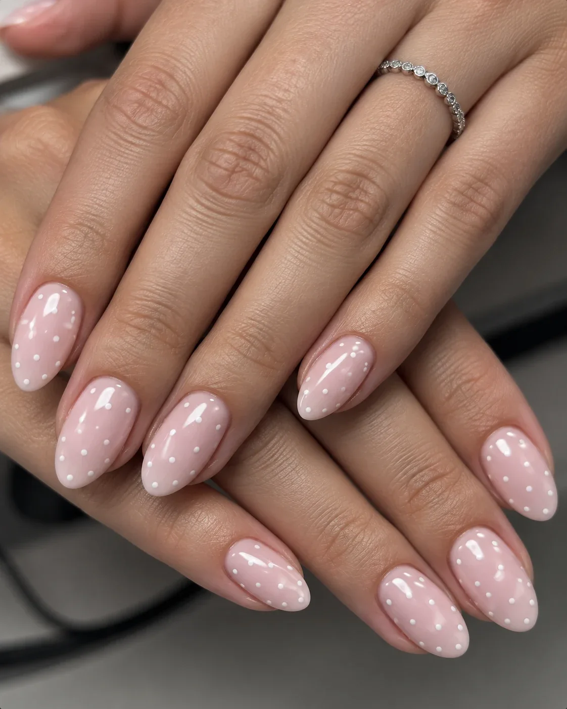 Amandelvormige roze nagels met witte stippen, ter inspiratie