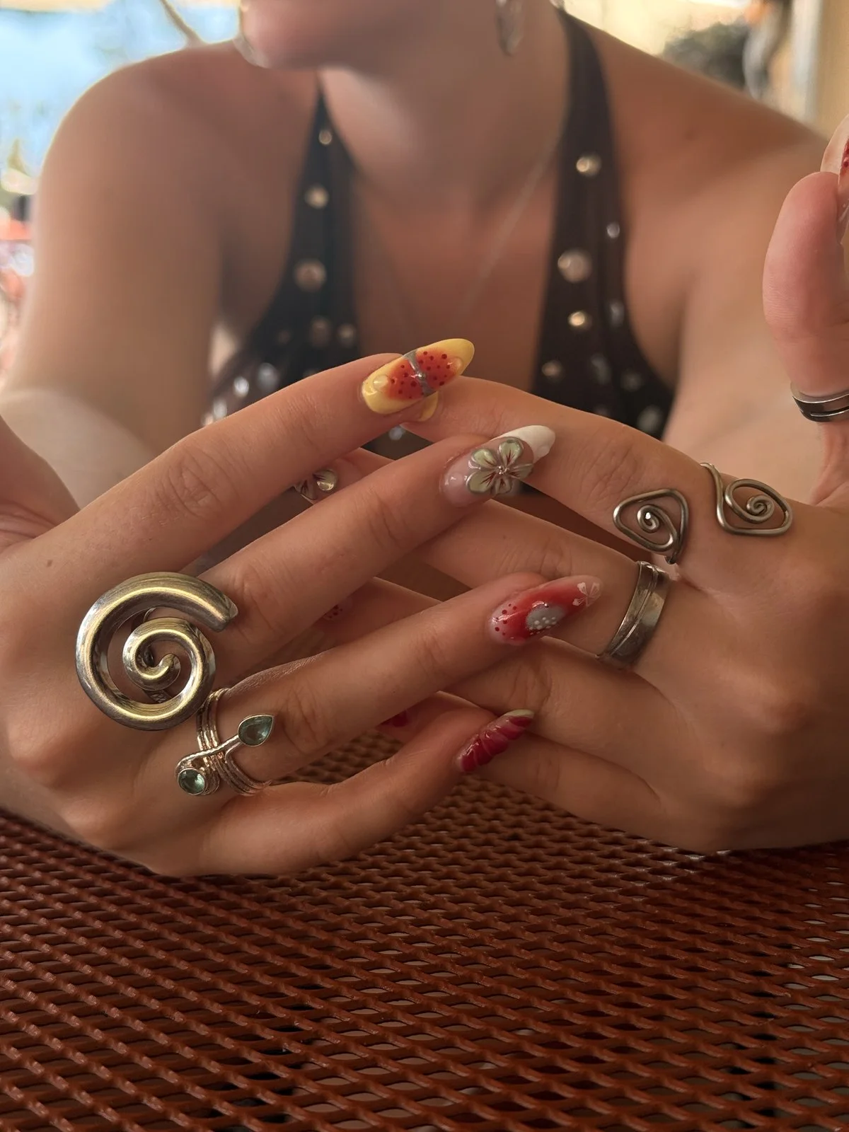 Detail van kleurrijke nail art met bloemen en zilveren ringen